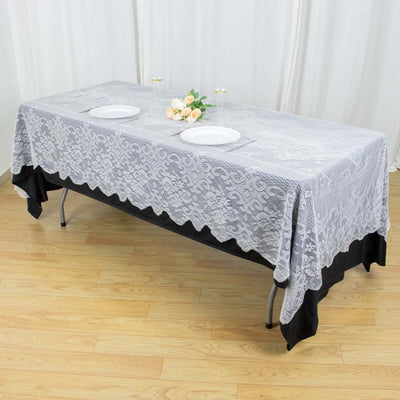 Gray lace tablecloth on a folding table with plates and flowers.
