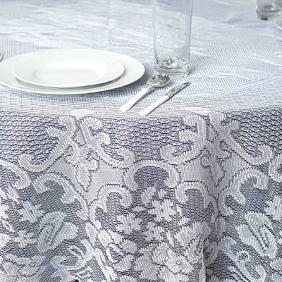 Elegant lace tablecloth on a dining table with plates and cutlery.