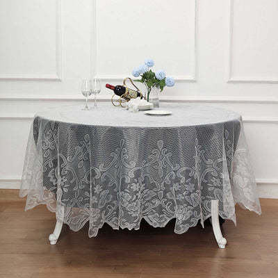 Elegant round lace tablecloth draped over a table with floral centerpiece and wine.