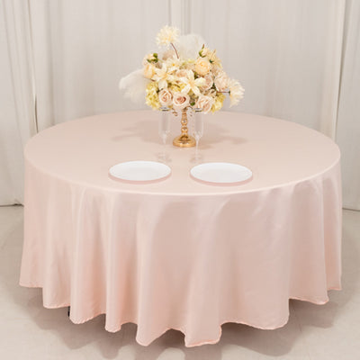 Elegant round table with a soft pink tablecloth and floral centerpiece.