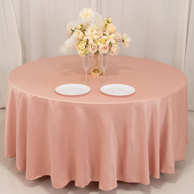 Round pink tablecloth with elegant floral centerpiece and two plates.