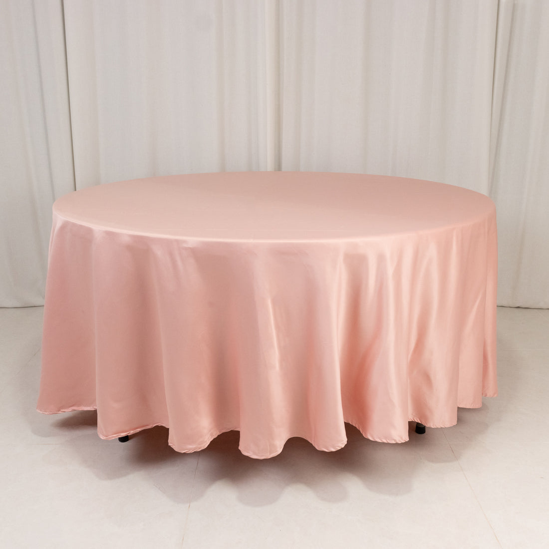 Round pink tablecloth draped over a table in a studio setting.