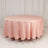 Round pink tablecloth draped over a table in a studio setting.