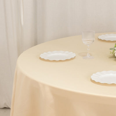 Elegant round table with beige tablecloth and white plates