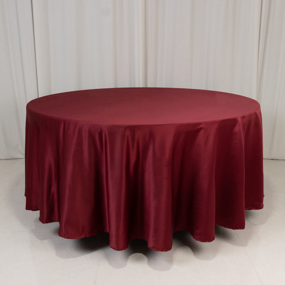 Round burgundy tablecloth on a plain backdrop