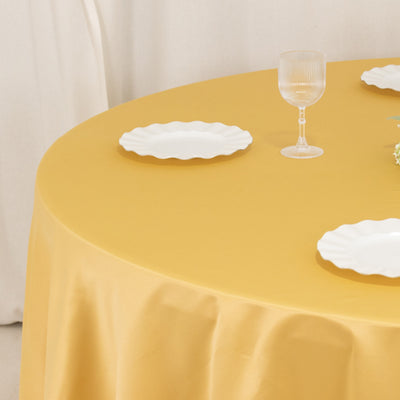 Yellow tablecloth with white dinnerware and a glass on a round table.