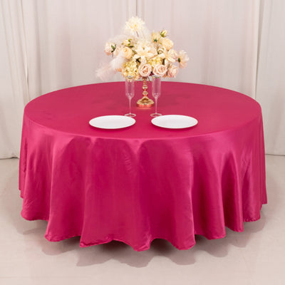 Round pink tablecloth with white plates and floral centerpiece.