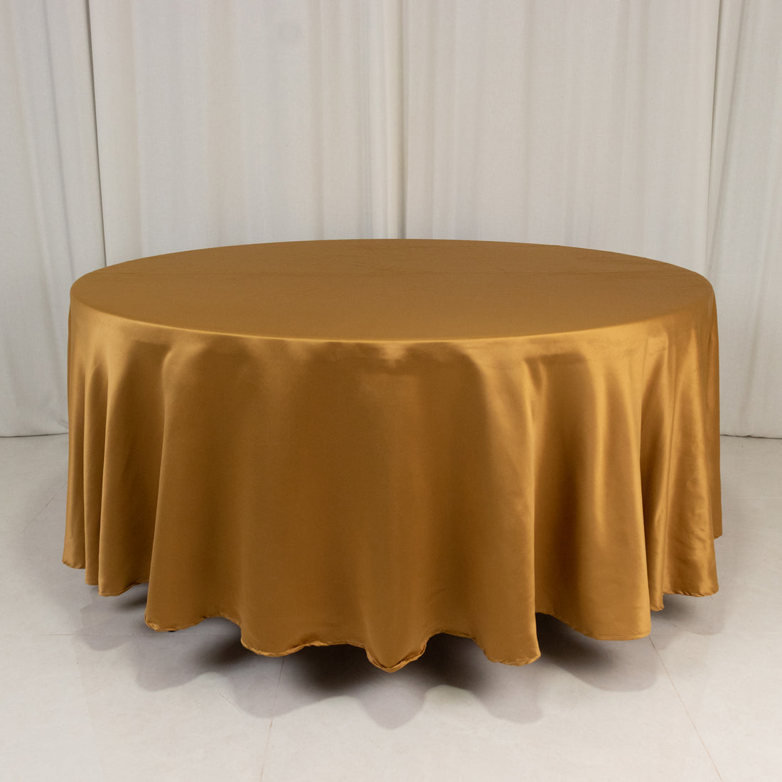 Round gold satin tablecloth on a white backdrop.