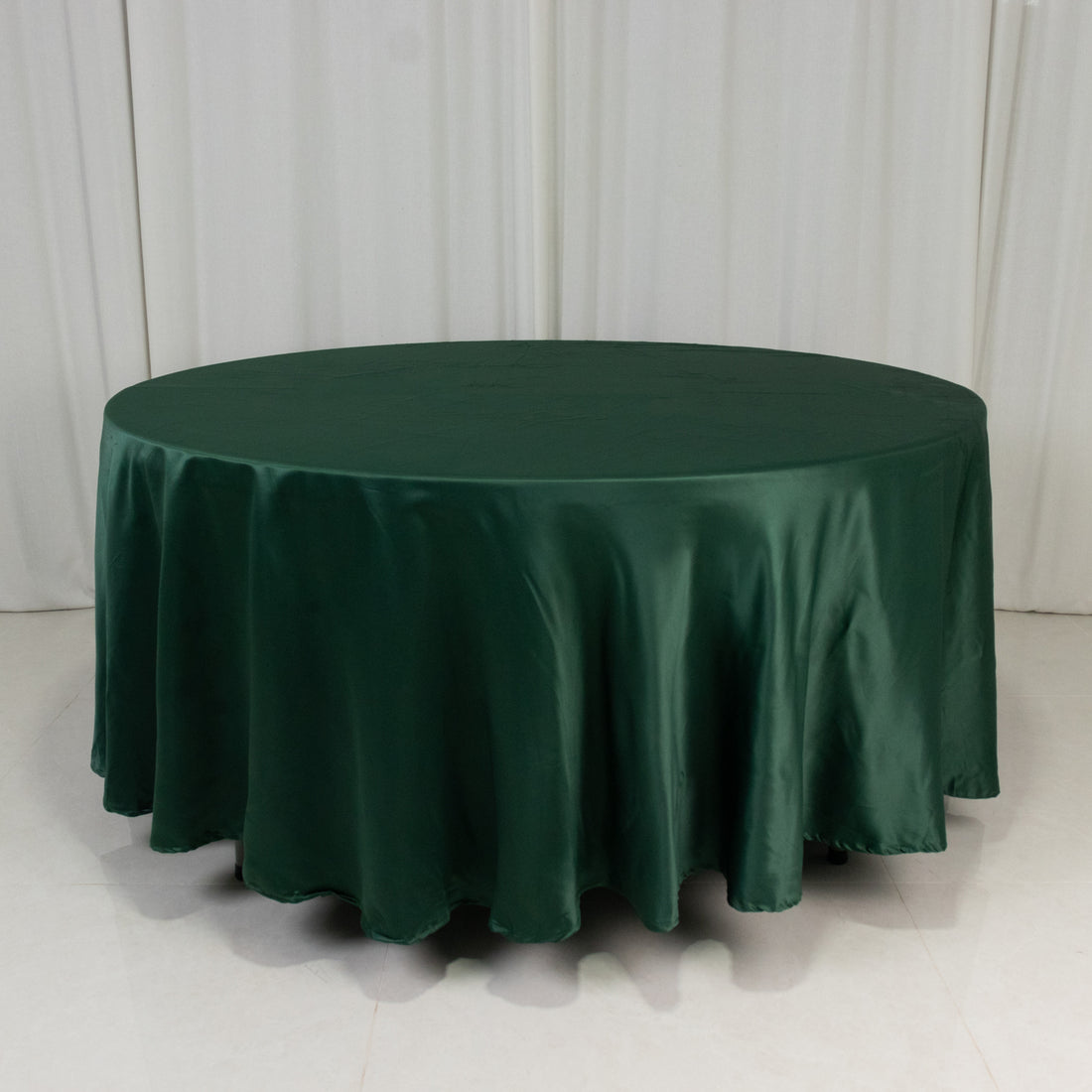 Round dark green tablecloth on a plain backdrop.