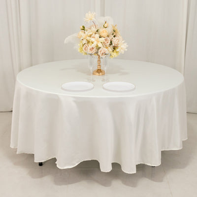 Round table with elegant white tablecloth and floral centerpiece.