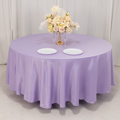 Round lavender tablecloth with floral centerpiece and two white plates.