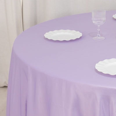 Round lavender tablecloth with white plates set on a table.