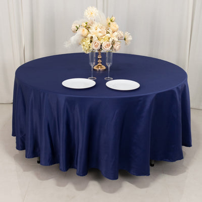 Navy round tablecloth with plates and floral centerpiece on a table.