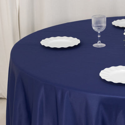 Navy tablecloth with white plates and glassware on a round table.
