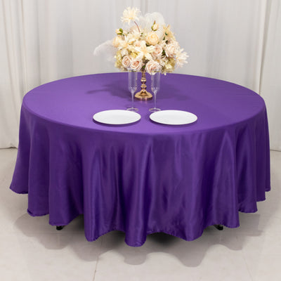 Round purple table with elegant floral centerpiece and white plates.