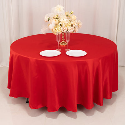 Red round tablecloth with floral centerpiece and plates.