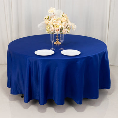 Navy blue tablecloth draped over a round table with floral arrangement and plates.