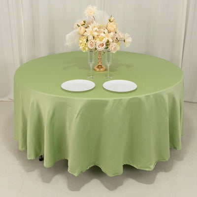 Round green tablecloth with white plates and floral centerpiece.