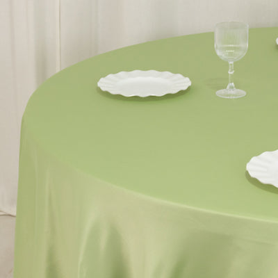 Green tablecloth with white plates and glassware on a round table.