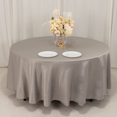Round table with elegant beige tablecloth and floral centerpiece.