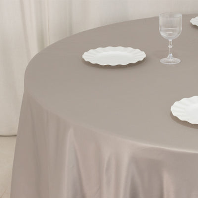Round table with beige tablecloth, white plates, and glass