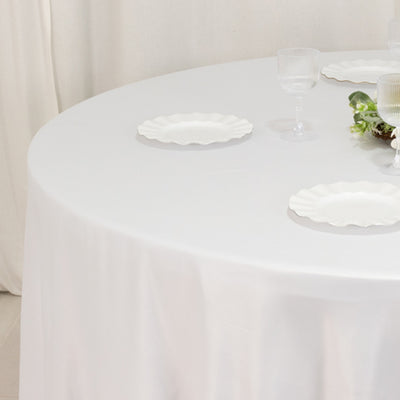 Round table set with white plates and glasses, elegant dining setup.