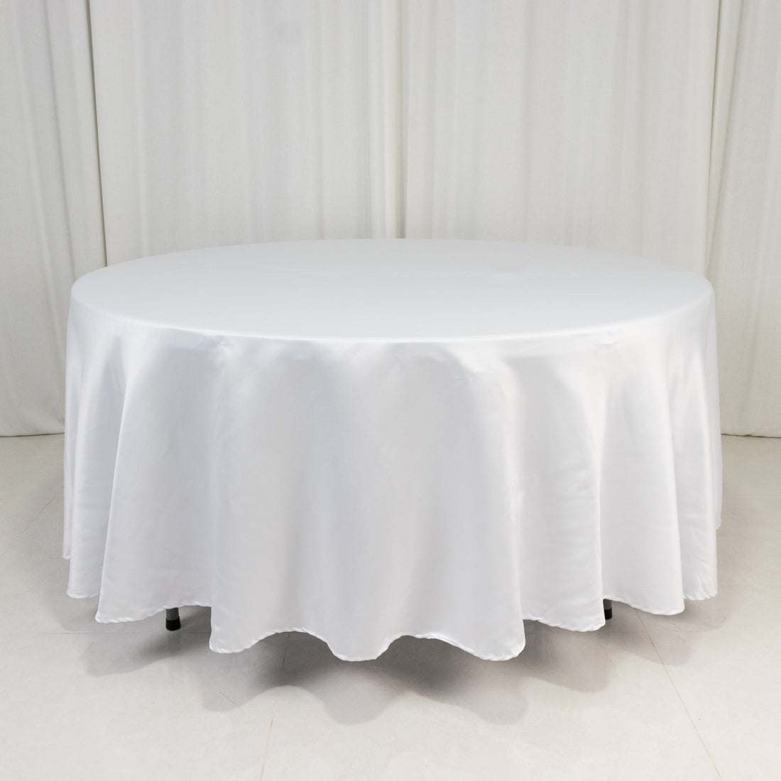 Round white table with a smooth tablecloth in a studio setting
