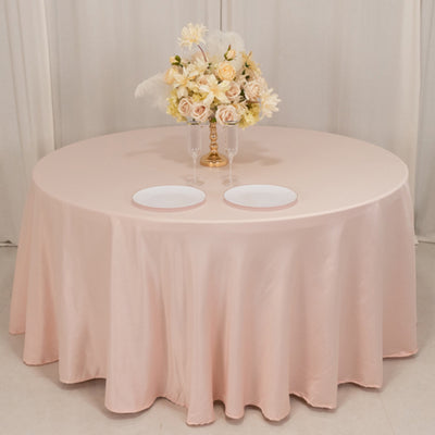 Elegant round table with a soft pink tablecloth and floral centerpiece.