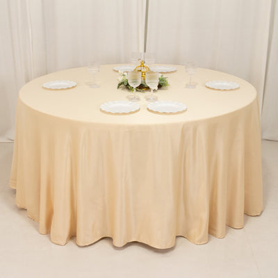 Round table set with a beige tablecloth and white plates, elegantly arranged for dining.