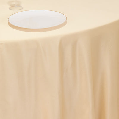 Beige tablecloth draped over a table with a white plate on top.