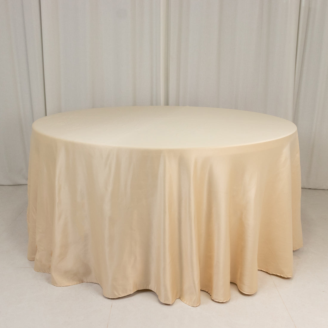 Beige round tablecloth draped over a table on a plain background.