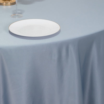 Elegant dining setting with a blue tablecloth, wine glass, and white plate.