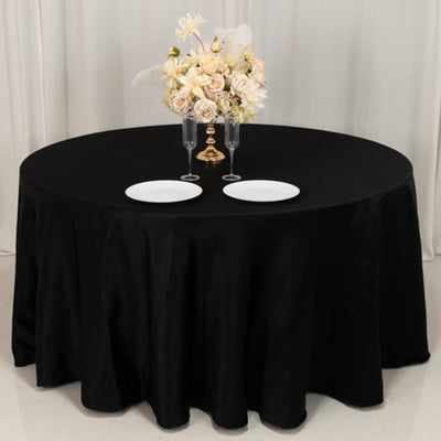 Black round table with elegant floral centerpiece and dinner plates.
