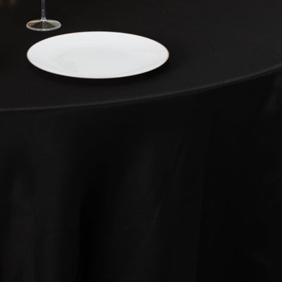 Elegant black table setting with white plate and wine glass.