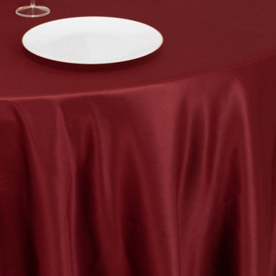 Burgundy satin tablecloth with a white plate on top.