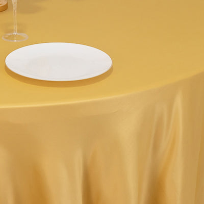 Elegant gold tablecloth draping over a table with a white plate on top.