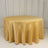Round golden tablecloth on a circular table against a plain backdrop.