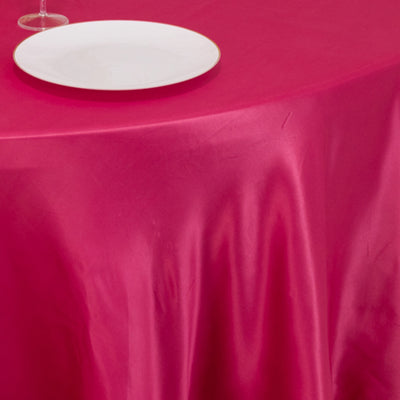 Pink satin tablecloth with a white plate on a dining table.