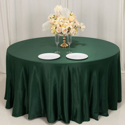 Round green tablecloth with elegant floral centerpiece and dinner plates.