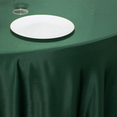 Green tablecloth with a white plate on a dining table.
