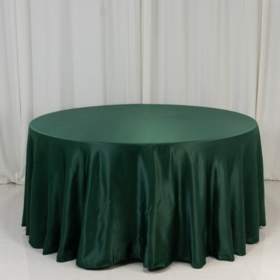 Green satin tablecloth draped over a round table in a studio setting.
