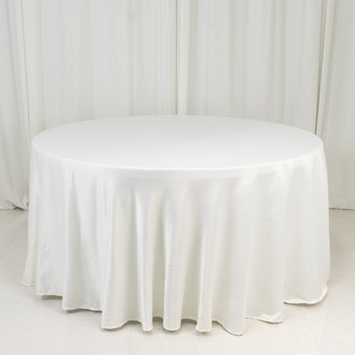 Round white table with a smooth tablecloth on a plain backdrop.