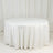 Round white table with a smooth tablecloth on a plain backdrop.