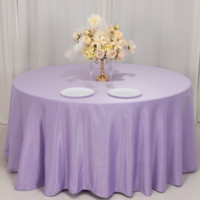 Round lavender tablecloth with elegant floral centerpiece and plates.