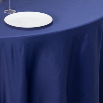 Navy tablecloth draped over a round table with a plate and glass on top.