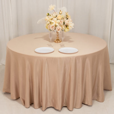 Round beige tablecloth with floral centerpiece and two plates.