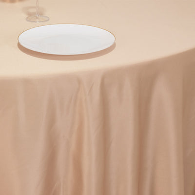 Elegant round table setting with a gold-rimmed plate on a beige tablecloth.