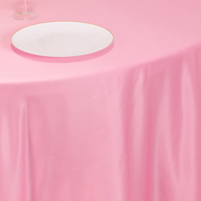 Elegant pink tablecloth draping over a table with a white plate on top.