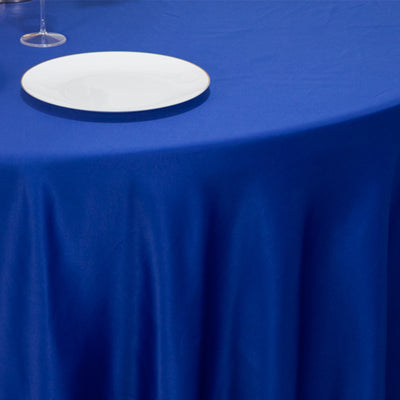 Blue tablecloth draped on a table with a white plate on top.