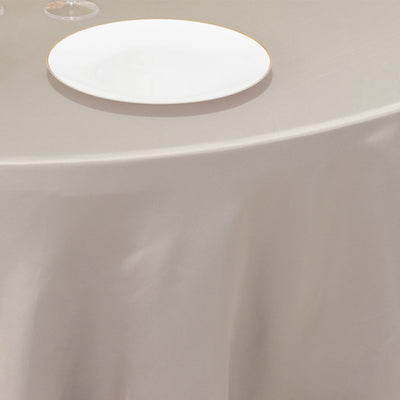 Elegant table setting with a white plate on a beige tablecloth.